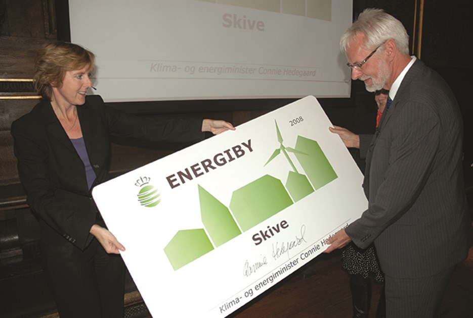 Skive Kommunes tidligere borgmester Flemming Eskildsen (V) modtager energibyskiltet fra Connie Hedegaard. Foto: Skive Kommune. 